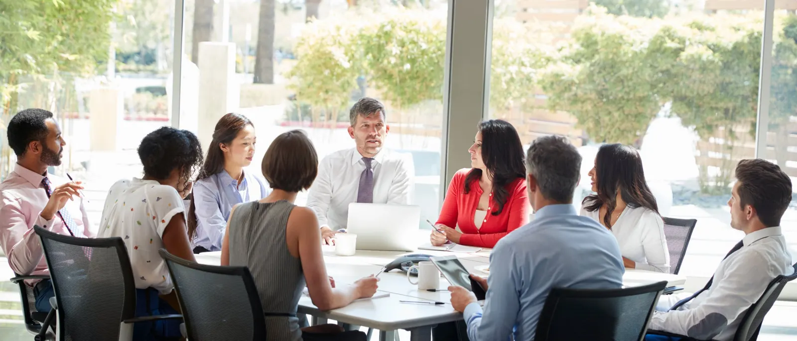 Business owners around a meeting table in a bright room, in discussion
